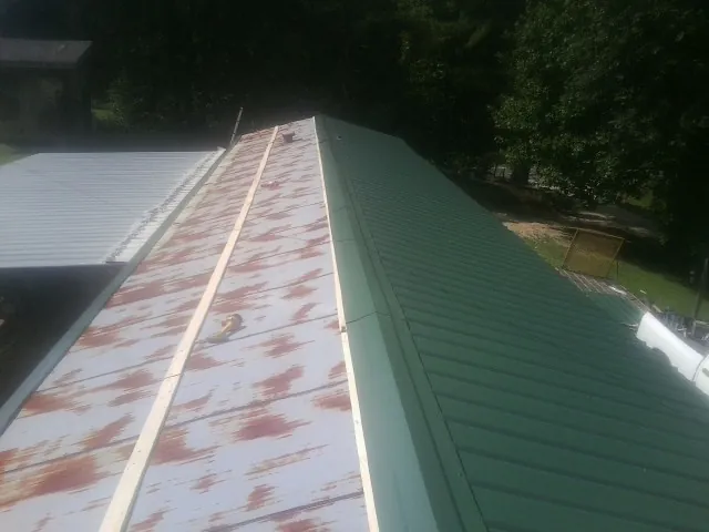 Old rusted panels beside newly installed green metal roofing — Wind Damage Roof Repair by Roofing Brothers in Altamonte Springs