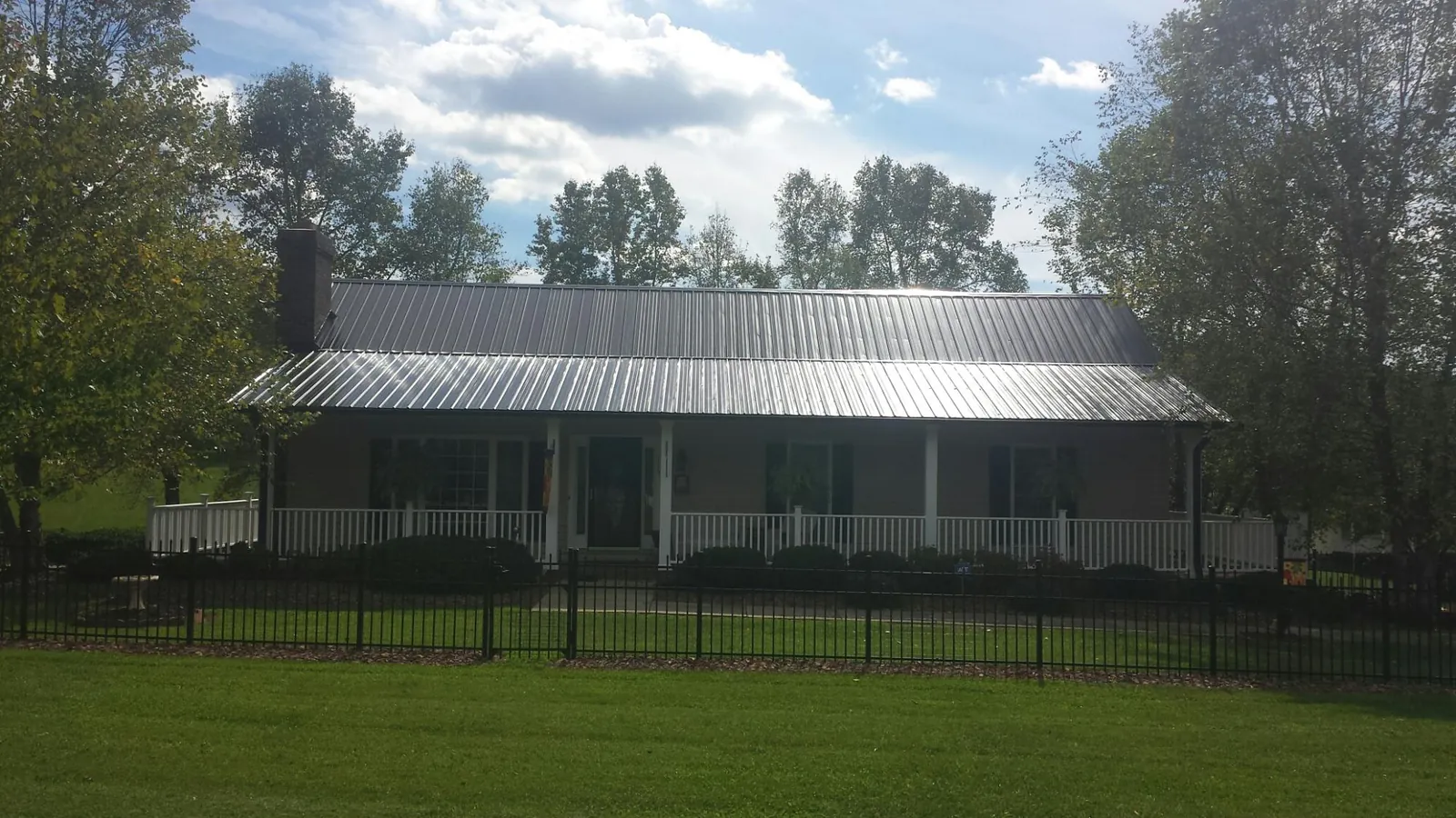 Gray metal roof on a brick ranch with a full width front porch — Gutter Guard Installation work by our crew in Altamonte Springs