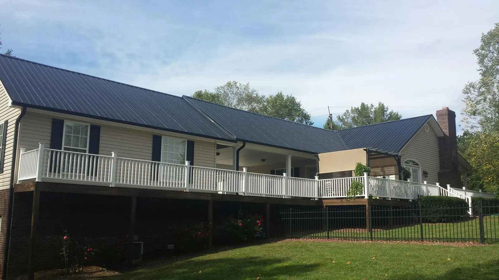 Black metal roof above a long white railed deck on a hillside home in Altamonte Springs