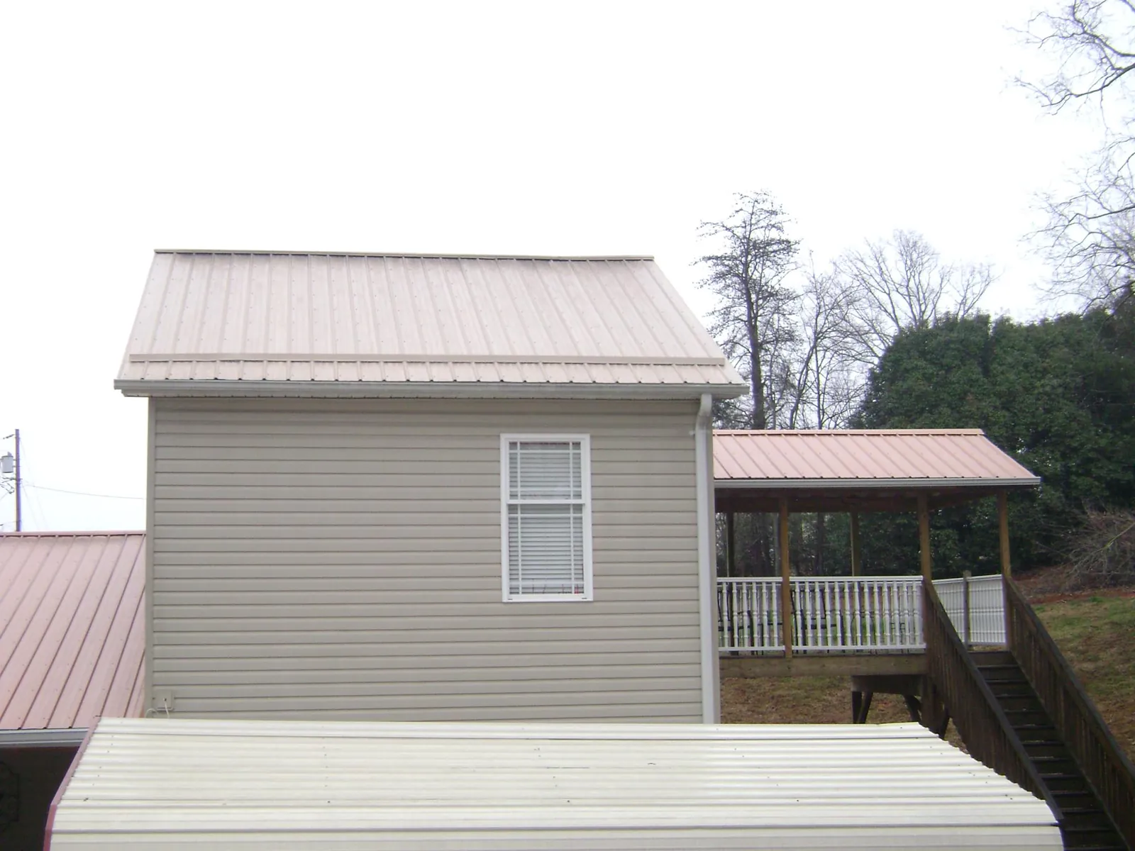 Tan metal roofs on a two story addition and attached porch, from a Roof Replacement job in Altamonte Springs